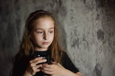 Elinde siyah tişörtlü kahve fincanı tutan küçük bir kız. Tasarımınızı ortaya koymak için mükemmel, alay edin.