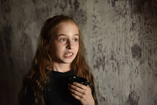 Little girl holding a coffee cup in black t-shirt. Mock up, perfect for putting your design on. — Stock Photo, Image