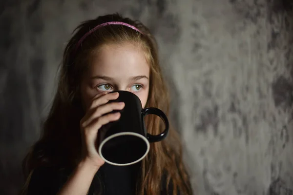 Маленька дівчинка тримає чашку кави в чорній футболці. Макет, ідеально підходить для розміщення вашого дизайну . — стокове фото