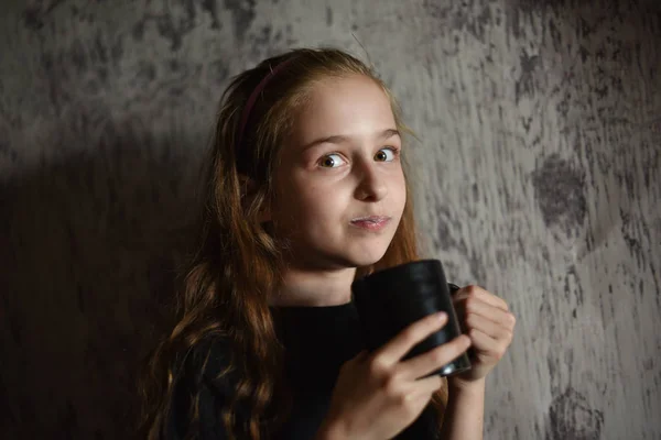 Little girl holding a coffee cup in black t-shirt. Mock up, perfect for putting your design on.