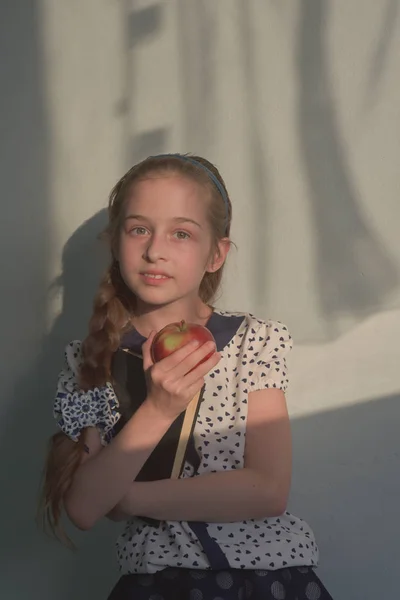 Söt Schoolgirl med rött äpple i handen ser ut som en strikt lärare. Pedagogiskt koncept. Skolans koncept. — Stockfoto