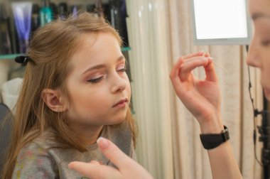 sahnede sahne almadan önce makyaj yapan küçük bir kız. Soyunma odasında performans öncesi hazırlık