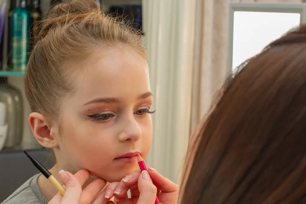 a little girl doing makeup before performing on stage. Preparation before the performance in the dressing room