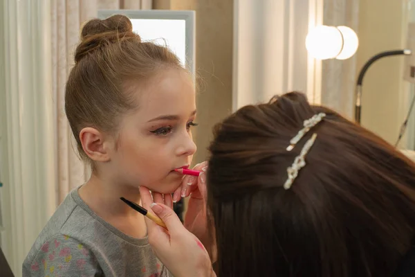 a little girl doing makeup before performing on stage. Preparation before the performance in the dressing room