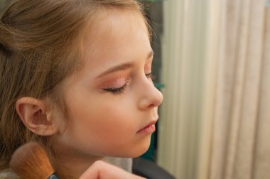 sahnede sahne almadan önce makyaj yapan küçük bir kız. Soyunma odasında performans öncesi hazırlık