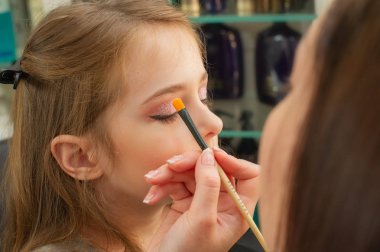sahnede sahne almadan önce makyaj yapan küçük bir kız. Soyunma odasında performans öncesi hazırlık