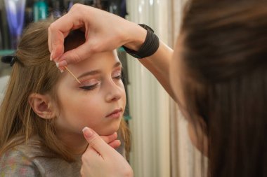 sahnede sahne almadan önce makyaj yapan küçük bir kız. Soyunma odasında performans öncesi hazırlık