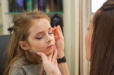 sahnede sahne almadan önce makyaj yapan küçük bir kız. Soyunma odasında performans öncesi hazırlık