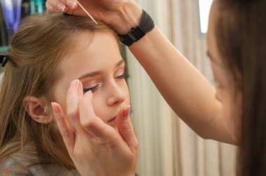 sahnede sahne almadan önce makyaj yapan küçük bir kız. Soyunma odasında performans öncesi hazırlık