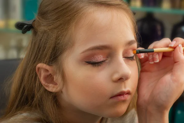 a little girl doing makeup before performing on stage. Preparation before the performance in the dressing room