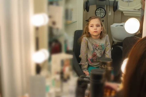 a little girl doing makeup before performing on stage. Preparation before the performance in the dressing room