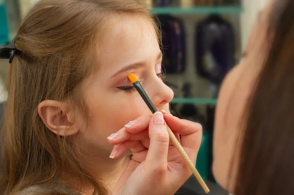 a little girl doing makeup before performing on stage. Preparation before the performance in the dressing room