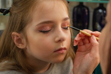 sahnede sahne almadan önce makyaj yapan küçük bir kız. Soyunma odasında performans öncesi hazırlık
