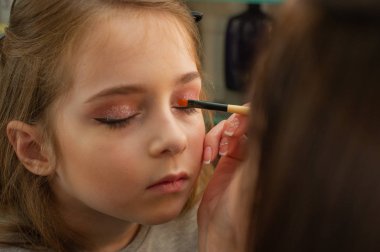 sahnede sahne almadan önce makyaj yapan küçük bir kız. Soyunma odasında performans öncesi hazırlık