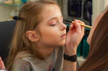 sahnede sahne almadan önce makyaj yapan küçük bir kız. Soyunma odasında performans öncesi hazırlık