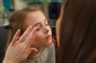 sahnede sahne almadan önce makyaj yapan küçük bir kız. Soyunma odasında performans öncesi hazırlık