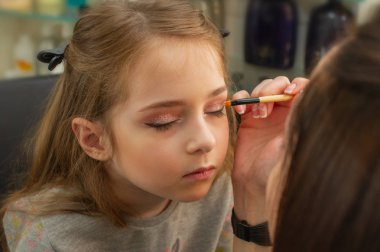 sahnede sahne almadan önce makyaj yapan küçük bir kız. Soyunma odasında performans öncesi hazırlık