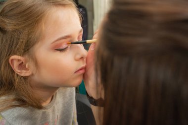 sahnede sahne almadan önce makyaj yapan küçük bir kız. Soyunma odasında performans öncesi hazırlık