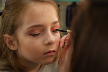 sahnede sahne almadan önce makyaj yapan küçük bir kız. Soyunma odasında performans öncesi hazırlık
