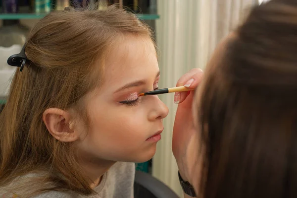 Ein kleines Mädchen, das sich schminkt, bevor es auf der Bühne auftritt. Vorbereitung vor dem Auftritt in der Garderobe — Stockfoto