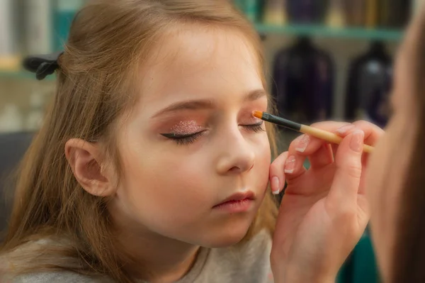Ein kleines Mädchen, das sich schminkt, bevor es auf der Bühne auftritt. Vorbereitung vor dem Auftritt in der Garderobe — Stockfoto