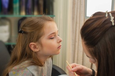 sahnede sahne almadan önce makyaj yapan küçük bir kız. Soyunma odasında performans öncesi hazırlık