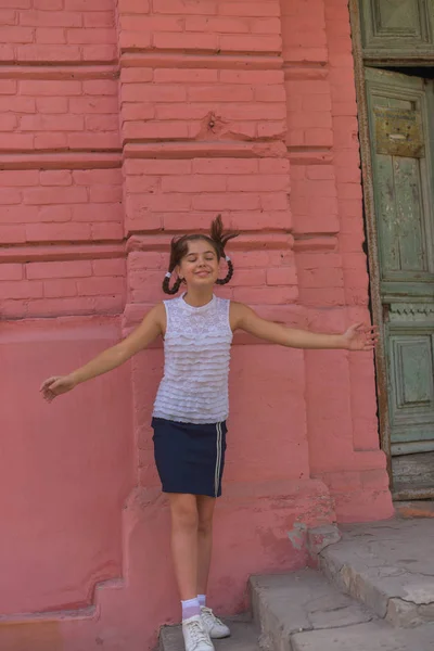 배경으로 빨간 벽돌 벽 근처 작은 아름다운 세련된 아이 소녀의 초상화를 닫습니다 — 스톡 사진