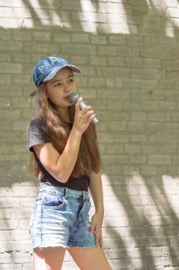 Tuğla duvar arka plan üzerinde mikrofon ile güzel küçük kız