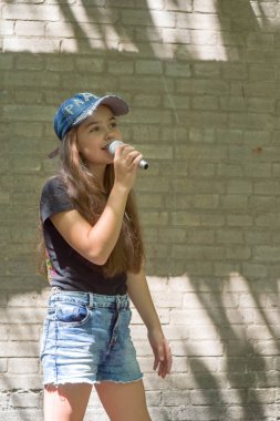 Tuğla duvar arka plan üzerinde mikrofon ile güzel küçük kız