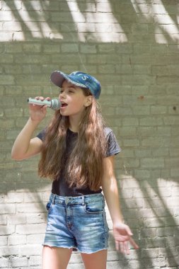 Tuğla duvar arka plan üzerinde mikrofon ile güzel küçük kız