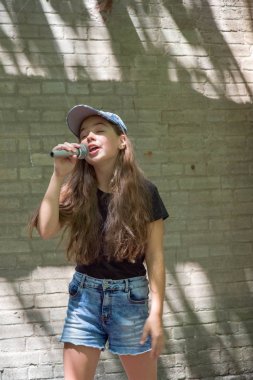 Tuğla duvar arka plan üzerinde mikrofon ile güzel küçük kız