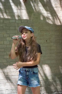 Tuğla duvar arka plan üzerinde mikrofon ile güzel küçük kız