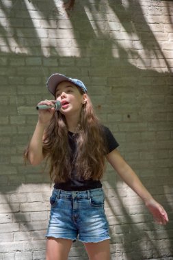 Tuğla duvar arka plan üzerinde mikrofon ile güzel küçük kız