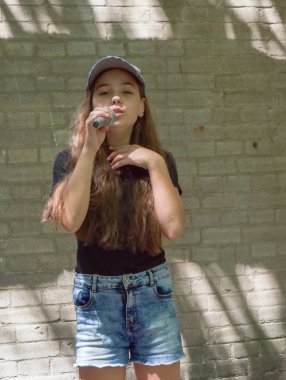 Tuğla duvar arka plan üzerinde mikrofon ile güzel küçük kız