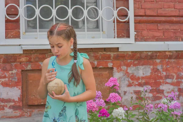 ダウンタウンの通りを歩くココナッツジュースを飲む魅力的な若い女性旅行者の肖像画。ライフスタイルコンセプト. — ストック写真
