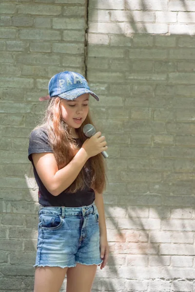 Belle petite fille avec microphone sur fond de mur de briques — Photo