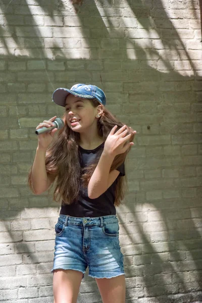 Belle petite fille avec microphone sur fond de mur de briques — Photo