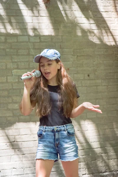 Belle petite fille avec microphone sur fond de mur de briques — Photo