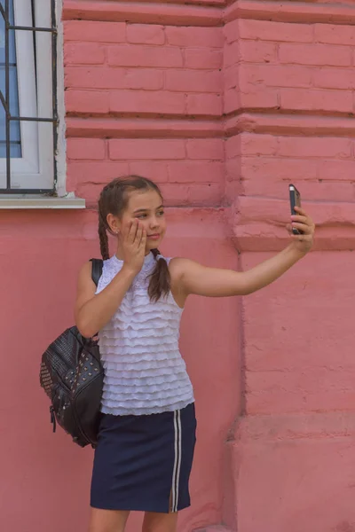 Primer plano retrato de pequeña niña hermosa y elegante cerca de la pared roja como fondo —  Fotos de Stock