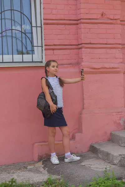 Közelről portré kis szép stílusos gyerek lány közelében vörös fal háttér — Stock Fotó