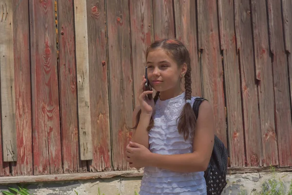 Ritratto ravvicinato di piccola bella ragazza alla moda vicino al muro rosso come sfondo — Foto Stock
