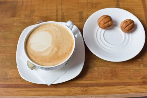 Cup of cappuccino and dessert cookies in the form of a nut
