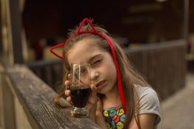 küçük kız kahverengi bir içki içiyor