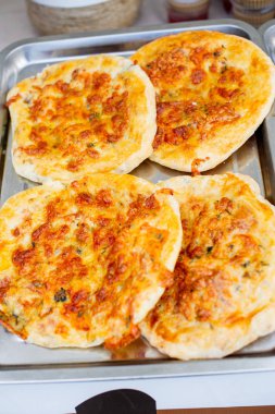 Küçük pizzalar. Dört küçük pizza metal bir tepsi ve parşömen üzerinde yalan.