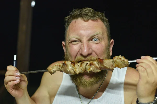 El barbudo come una deliciosa barbacoa. Un hombre con barba roja come brochetas de brochetas —  Fotos de Stock