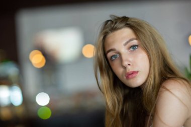 Mavi gözlü bir kız şehir kafede oturuyor. kahverengi dalgalı saç modeli ile kadın. Yaşam tarzı kavramı.