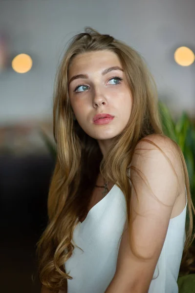 Menina com olhos azuis sentada no café urbano. mulher com penteado ondulado marrom. Conceito de estilo de vida . — Fotografia de Stock