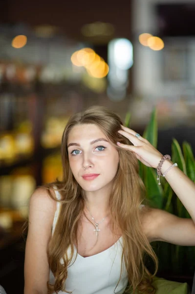 Mädchen mit blauen Augen, die auf einem städtischen Café sitzen. Frau mit brauner welliger Frisur. Lifestylekonzept. — Stockfoto