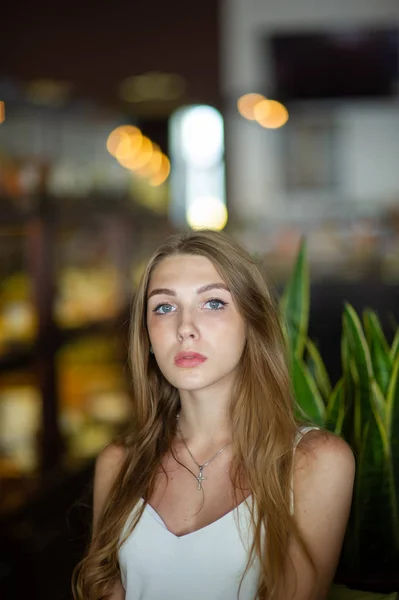 Дівчина з блакитними очима сидить у міському кафе. жінка з коричневою хвилястою зачіскою. Концепція стилю . — стокове фото