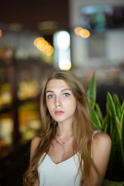 蓝眼睛的女孩坐在城市咖啡馆。女人与棕色波浪发型。生活方式理念. — 图库照片